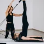 Donna che pratica Pilates sul Reformer in uno studio con molle e carrello mobile