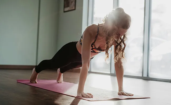 Donna in posizione plank che esegue retrazione e protrazione attiva delle scapole senza muovere la colonna